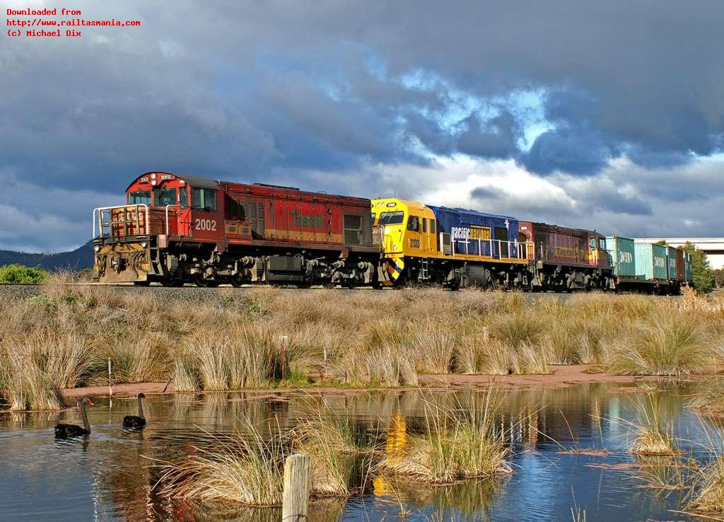 On 28 July, the last day of the old timetable, train 736 from Hobart is hauled by the mixed DQ-MKA-DQ trio of 2002-2133-2011 as the train heads north past Goulds Lagoon. The pair of swans are obviously unperturbed by the passing train.