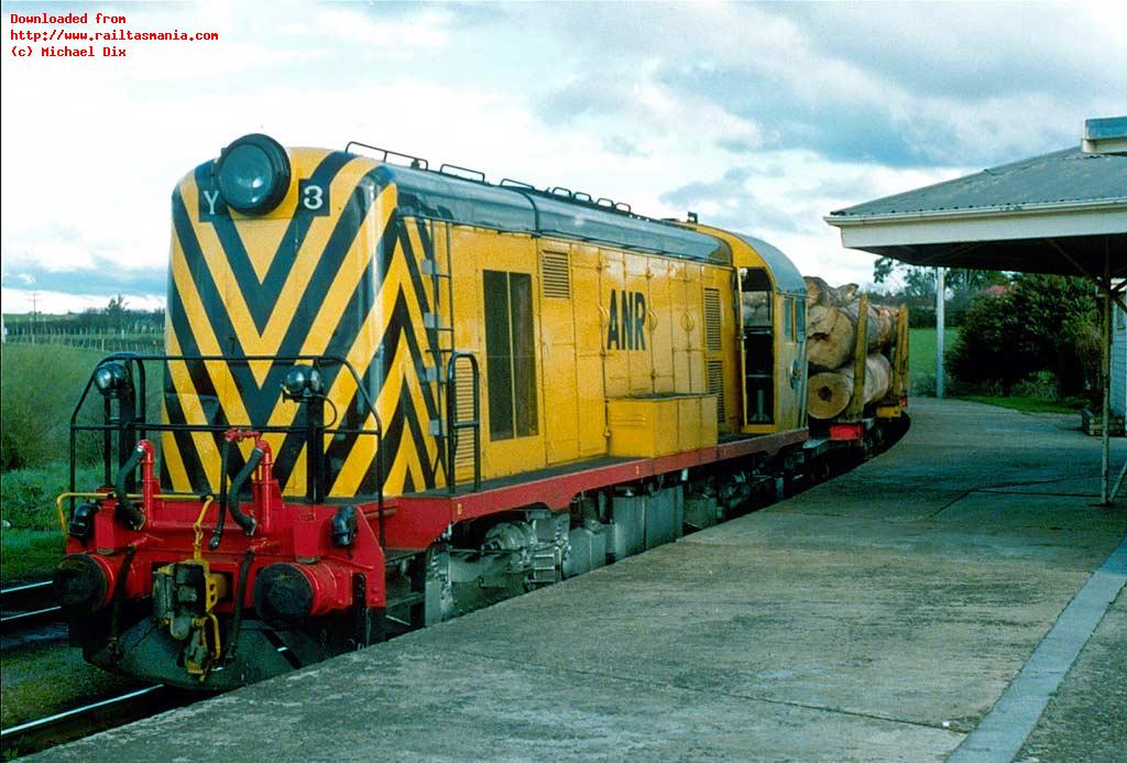 A clean Y3, probably shut down and being transferred to Launceston workshops, sits at the platform at Western Junction with a loaded log train as it waits for additional locos before continuing north. September 1980